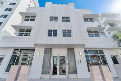 a white building with a palm tree in front of it at Cozy Miami Beach Apartment walking distance to Beach and Ocean in Miami Beach