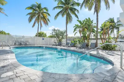a swimming pool with palm trees in a resort at Cozy Miami Beach Apartment walking distance to Beach and Ocean in Miami Beach