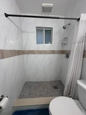 a bathroom with a shower with a toilet and a window at Cozy room close to everything, 5min to the airport in Miami