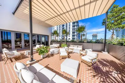 a patio with white couches and tables and chairs at Modern and Cozy 1BD Apt with Gym & Pool in Miami