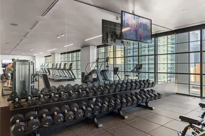 a gym with rows of exercise equipment and a flat screen tv at 2105 Modern studio with Balcony a Pool and a 24 hour Gym in Downtown Miami in Miami
