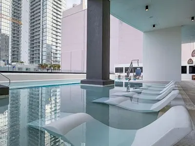 a swimming pool with white chairs and some buildings at City Skyline Views & Rooftop Pool at District 225 in Miami
