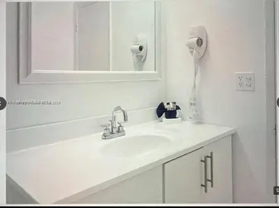 a white bathroom with a sink and a mirror at Beautiful Apartment in Sunny Isles Beach in Sunny Isles Beach