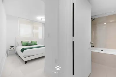 a white bedroom with a bed and a shower at Luxury Coastal Escape Balcony views - Free Parking in Miami Beach