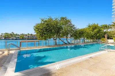 a large swimming pool with trees in the background at Luxury Coastal Escape Balcony views - Free Parking in Miami Beach