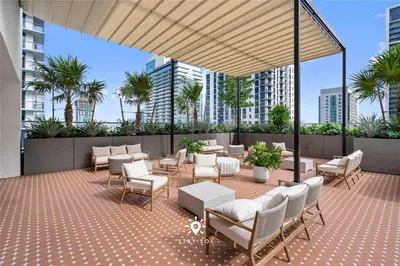 a patio with tables and chairs and palm trees at High Rise Haven with Pool Cowork & Spa in Miami in Miami