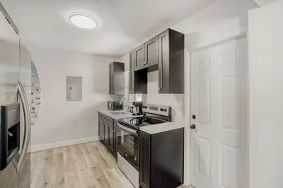 a kitchen with black appliances and white cabinets at Lauderdale Breeze Villas - Luxury 3 BR Coastal Retreat in Fort Lauderdale