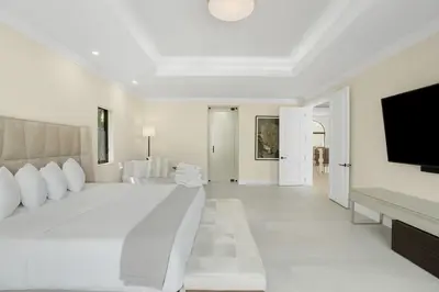 a white bedroom with a large bed and a flat screen tv at WATERFRONT MANSION Las Olas in Fort Lauderdale