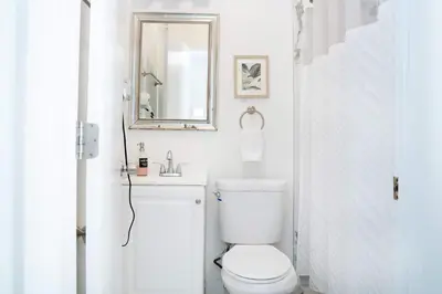 a white bathroom with a toilet and a mirror at Mar & Luna Family retreat in Miami