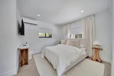 a white bedroom with a white bed and a window at Waterfront Unit #1 20 Min Walk to Beach and Shops in Fort Lauderdale