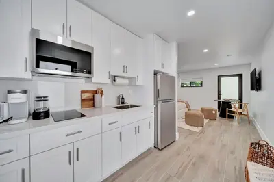 a white kitchen with a refrigerator and a table at Waterfront Unit #5 20 Min Walk to Beach and Shops in Fort Lauderdale