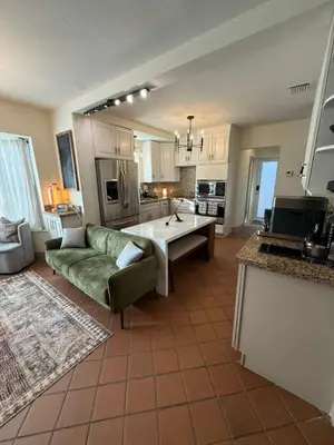 a living room with a green couch and a kitchen at Trio in Miami