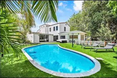 a large swimming pool in front of a house at Sunny Miami Escape in Prime Location