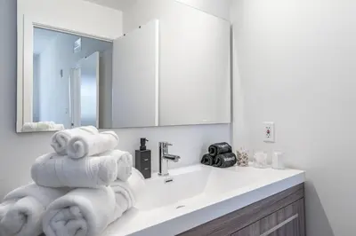 a bathroom with a sink and a pile of towels at Classy 2BR-2BA Oasis Beach Pool Parking EV Station in Hallandale Beach