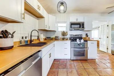 a kitchen with white cabinets and stainless steel appliances at 5 Mi to Las Olas Beach! Bright Home with Fenced Yard in Fort Lauderdale