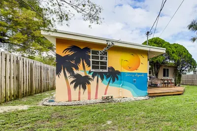 a house with a mural of palm trees on it at 5 Mi to Las Olas Beach! Bright Home with Fenced Yard in Fort Lauderdale