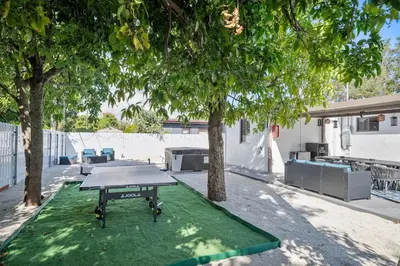 a ping pong table on a green mat under two trees at Miami Hotel Home in North Miami