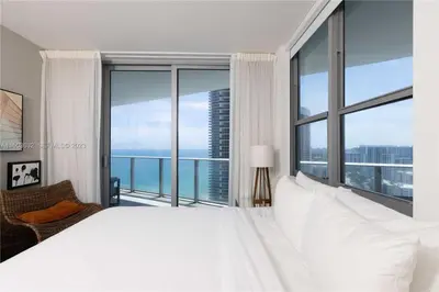 a bedroom with a large white bed and large windows at Oceanfront dream W pool & beach access in Hollywood