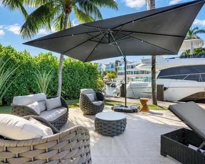 a patio with furniture and an umbrella and a boat at The Rendez-Vous Villa Waterfront in Fort Lauderdale