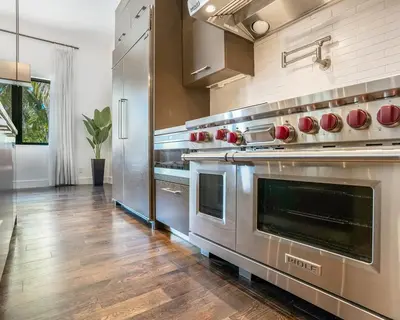 a large kitchen with stainless steel appliances and wooden floors at The Rendez-Vous Villa Waterfront in Fort Lauderdale