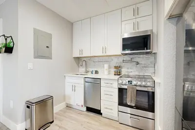 a kitchen with white cabinets and stainless steel appliances at The Palms A in Fort Lauderdale