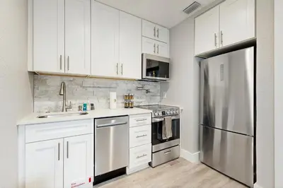 a kitchen with white cabinets and a stainless steel refrigerator at The Palms A in Fort Lauderdale
