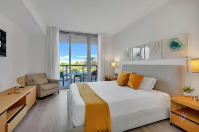 a bedroom with a large bed and a balcony at Spectacular Near Beach 2 BR Apartment in Hallandale Beach