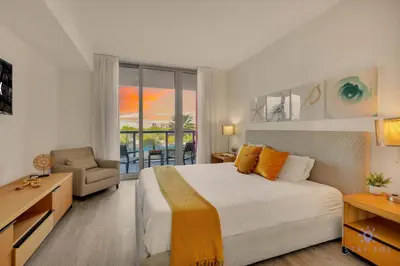 a bedroom with a bed and a chair and a window at Spectacular Near Beach 2 BR Apartment in Hallandale Beach