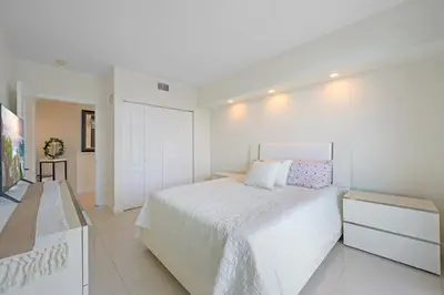 a white bedroom with a bed and a tv at Spacious 3BR Condo Across from Beach with Ocean & City Views in Sunny Isles Beach