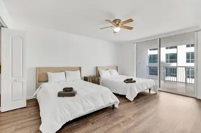 a white bedroom with two beds and a ceiling fan at Upscale4 Brickell Retreat with Bay n City Views in Miami