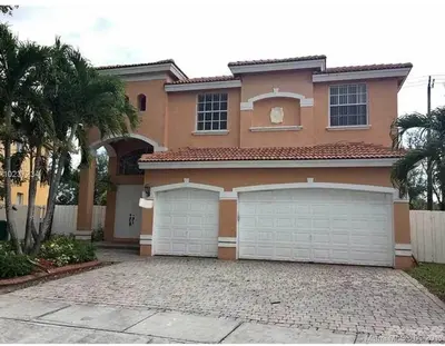a large house with two garage doors in a driveway at The B Shared Resident in Miramar