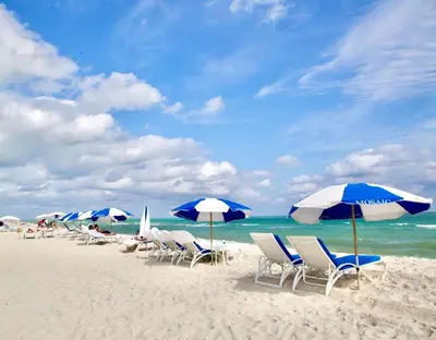 a group of chairs and umbrellas on a beach at Cozy3 Miami Beach Getaway Quick Walk to the Ocean in Miami Beach