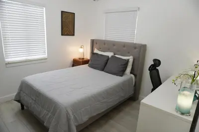 a bedroom with a bed and a table with a lamp at Pool House in Fort Lauderdale in Fort Lauderdale