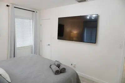 a bedroom with a bed with a flat screen tv on the wall at Pool House in Fort Lauderdale in Fort Lauderdale