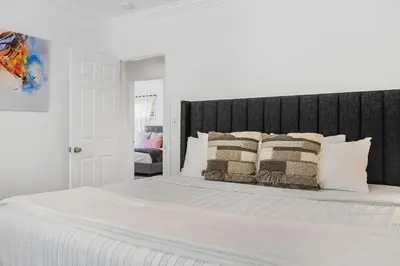 a white bed with a black headboard and pillows at Spacious Miami Home with Private Pool & Parking in Biscayne Park