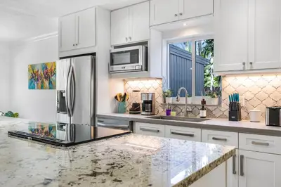 a kitchen with white cabinets and a stainless steel refrigerator at Spacious Miami Home with Private Pool & Parking in Biscayne Park
