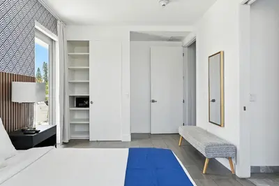 a bedroom with a white bed and a blue rug at Apto 2 Quartos c/ Varanda South Beach Central in Miami Beach