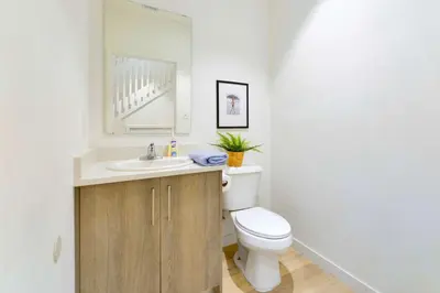 a bathroom with a toilet and a sink and a mirror at Miami Townhouse Stay with Free Parking in Miami