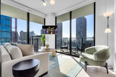a living room with a couch and a chair and large windows at Corner Chic 2 Bedroom Downtown with Rooftop Pool & Views in Miami