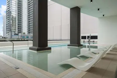 a swimming pool with white chairs in a building at Well-Located Condo with Free Parking and Amenities in Miami