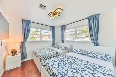 two beds in a bedroom with blue curtains at Oasis of Love and Joy Family in Miami