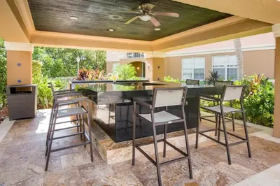 an outdoor kitchen with a black counter and stools at The Yacht Club at Aventura Miami 6307 in South Island