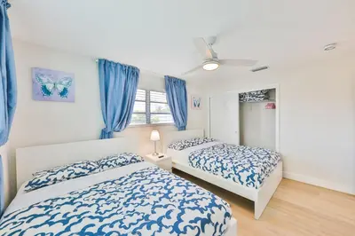 two beds in a bedroom with blue curtains at Family Poolside Palm Retreat with Jacuzzi in Hollywood
