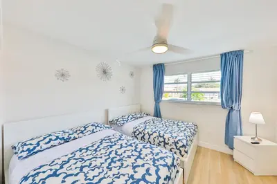 a bedroom with two beds and a window with blue curtains at Family Poolside Palm Retreat with Jacuzzi in Hollywood