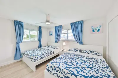 a bedroom with two beds and blue curtains at Family Poolside Palm Retreat with Jacuzzi in Hollywood