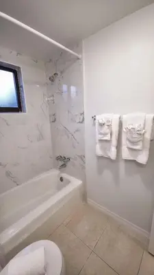 a white bathroom with a tub and a toilet and towels at Apartment close to shops & beach-Free Parking 109 in Hollywood