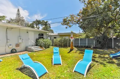a yard with blue chairs and a house at Heart of Hollywood Villa in Hollywood