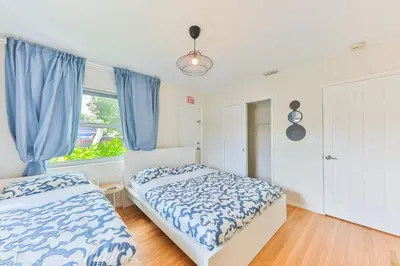 a bedroom with two beds and a window with blue curtains at Heart of Hollywood Villa in Hollywood