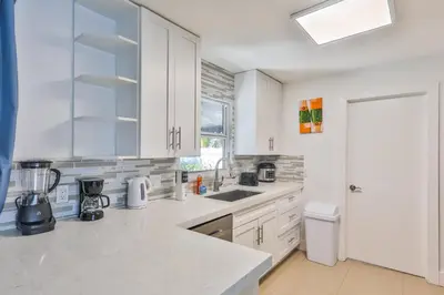 a white kitchen with white cabinets and a sink at 50 Shades of Grey on the Canal Villa STR-4500 in Fort Lauderdale