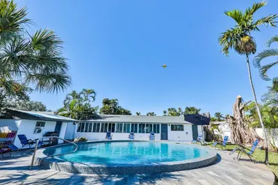 a swimming pool in front of a house with palm trees at 50 Shades of Grey on the Canal Villa STR-4500 in Fort Lauderdale